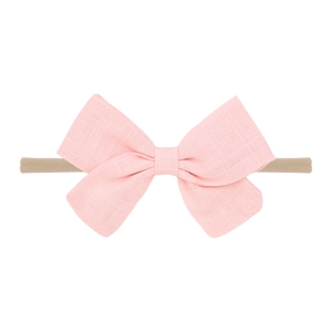Close-up of pink textured cotton bow on beige soft seamless nylon headband for baby