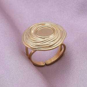 Detail of a golden open ring featuring a large round disc with spiral textures on silk
