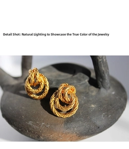 Macro shot of vintage gold twisted rope double hoop earrings on a grey ceramic surface
