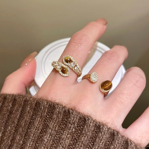 Detail of gold-plated tiger eye rings with zircon accents on a soft autumn knit