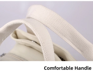 Detail of reinforced thick canvas handle and smooth metal zipper on ivory tote bag