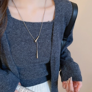 Minimalist silver water drop pendant necklace styled on a dark grey knitted sweater