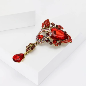 Detail of vintage gold brooch with red teardrop stone on white geometric stands