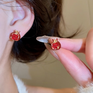 Detailed view of red pomegranate studs with gold plating and sparkling red crystals