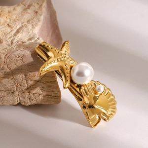 Detail of golden starfish and shell hair clip with pearls on a natural stone base