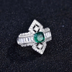 Top-down view of cushion-cut green gemstone ring with pavé-set diamonds on black texture