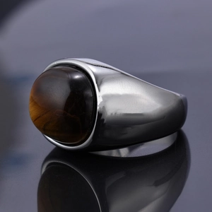 Macro side view of polished silver ring featuring an oval tiger eye stone on black surface