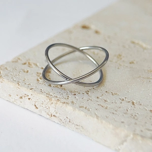 Detail shot of a silver interlaced double ring set on a natural travertine stone surface