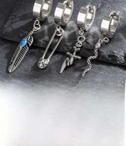 Detailed view of silver titanium steel earrings with feather, pin, skull, and snake charms