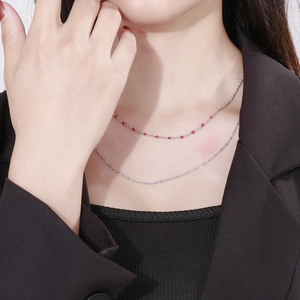Double-layered silver necklace with delicate chains and elegant red enamel bead detail