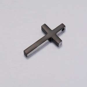 Macro shot of black brushed metal cross pendant with detailed surface texture