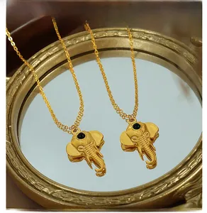 Macro shot of gold elephant pendant necklaces with black gem eyes on reflective mirror