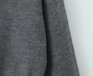 Détail en gros plan de la texture du tricot gris et du motif de tissage sur le vêtement
