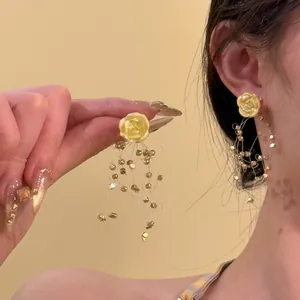Detail of yellow resin rose earrings with long golden bead tassel fringe charms