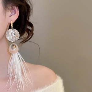 Détail de boucles d'oreilles bohèmes en plumes blanches avec disques en résine