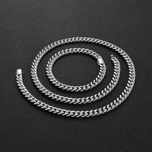Detailed overhead view of three silver Cuban link chains on a black textured background