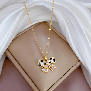 Détail d'un collier papillon doré avec des motifs à carreaux noirs et blancs et cristaux