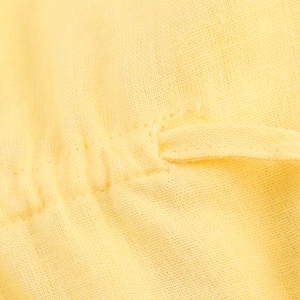 Detailed macro view of yellow linen blend fabric texture and pleat stitching on the shirt