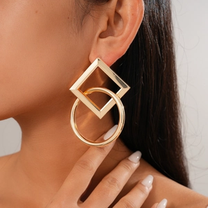 Close-up of geometric gold interlocking square and circle earrings on a model