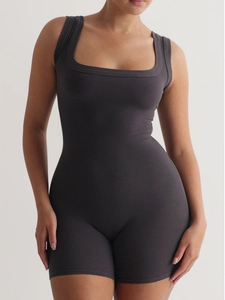 Side view of dark grey ribbed yoga jumpsuit with U-neck design on a standing model