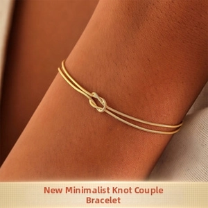 Dettaglio del bracciale dorato con nodo minimalista indossato sul polso da una donna