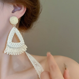 Détail de boucles d'oreilles bohèmes en raphia avec texture et design triangulaire