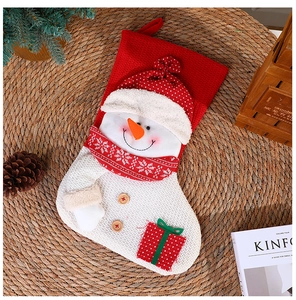 Nahaufnahme eines rot-weißen Strick-Weihnachtsstrumpfes mit Schneemann-Motiv und Geschenken