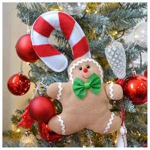 Close-up of plush gingerbread man and candy cane hanging on a decorated Christmas tree