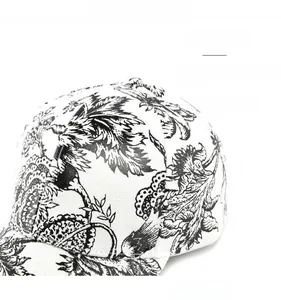 Dettaglio della stampa floreale nera su un cappellino bianco con cuciture rifinite a mano