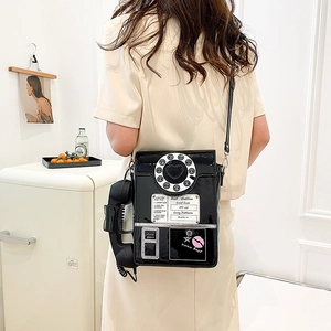 Detail of vintage telephone crossbody bag in black patent leather worn over the shoulder