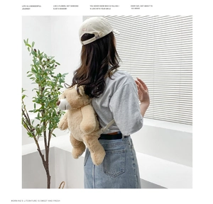 Detail of light brown teddy bear plush backpack with adjustable straps on model