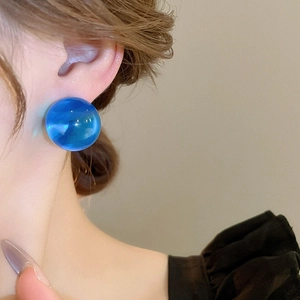 Gros plan d'un clou d'oreille en résine bleue translucide porté par un mannequin
