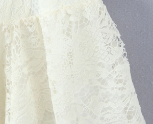 Detailed close-up of white floral lace fabric texture on this French style V-neck dress