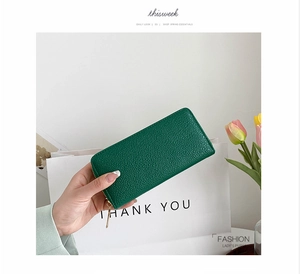 Close-up of emerald green long zipper wallet in litchi grain leather held by hand