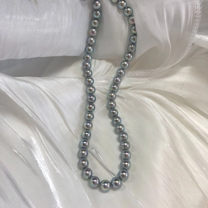 Macro shot of silver-blue Akoya style pearl necklace on white satin fabric
