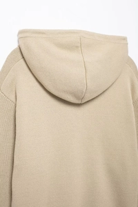 Detailed macro view of beige knitted hoodie back showing premium fabric texture and hood