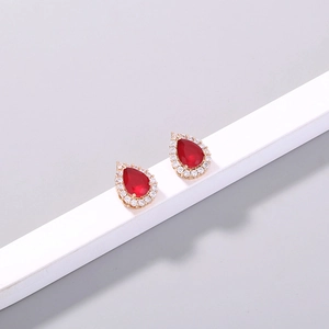 Detail of pear-cut red stone earrings with gold plating and white micro-set crystals