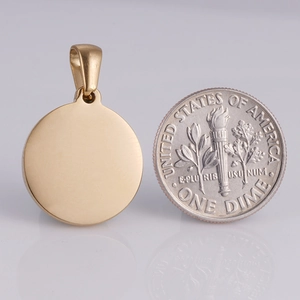 Pendentif rond poli plaqué or 18K à côté d'une pièce pour comparer la taille