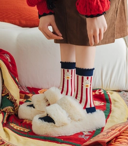 Close-up of fluffy cream plush slippers paired with festive red striped rabbit socks