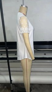 Detail of white V-neck top showing delicate lace sleeves with cross embroidery patterns