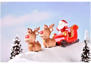 Macro shot of resin Christmas reindeer and Santa in a red sleigh on a snowy landscape