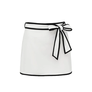 Detail of white mini skirt with black contrast piping and an elegant bow at the waist