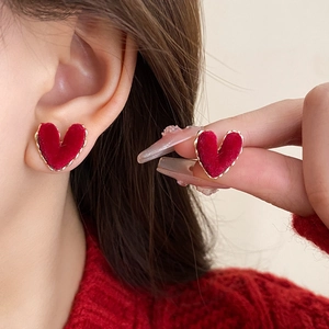 Detail of red velvet heart earrings with gold twisted rope edge on model's ear