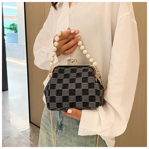 Detail of checkered denim evening bag with large pearl handle and gold chain strap