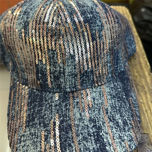 Detailed macro view of rose gold sequins on dark blue denim baseball cap fabric