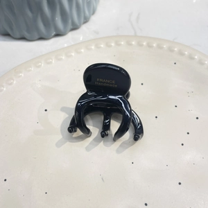 Close-up of black acetate octopus hair claw with gold France Handmade logo on ceramic