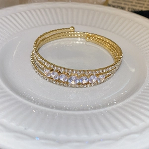 Multilayer gold wrap bracelet with zircons and sparkling crystals in a ceramic dish