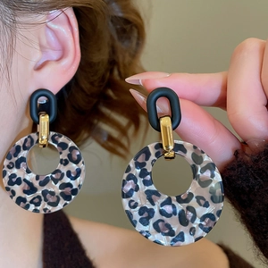 Close-up of retro leopard print acrylic earrings with matte black studs and golden links