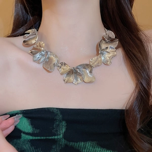 Macro detail of silver leaf pendant necklace showing fine brushed metal texture and layering