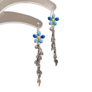 Vintage style drop earrings with blue enamel flowers and silver leaf tassels on white background